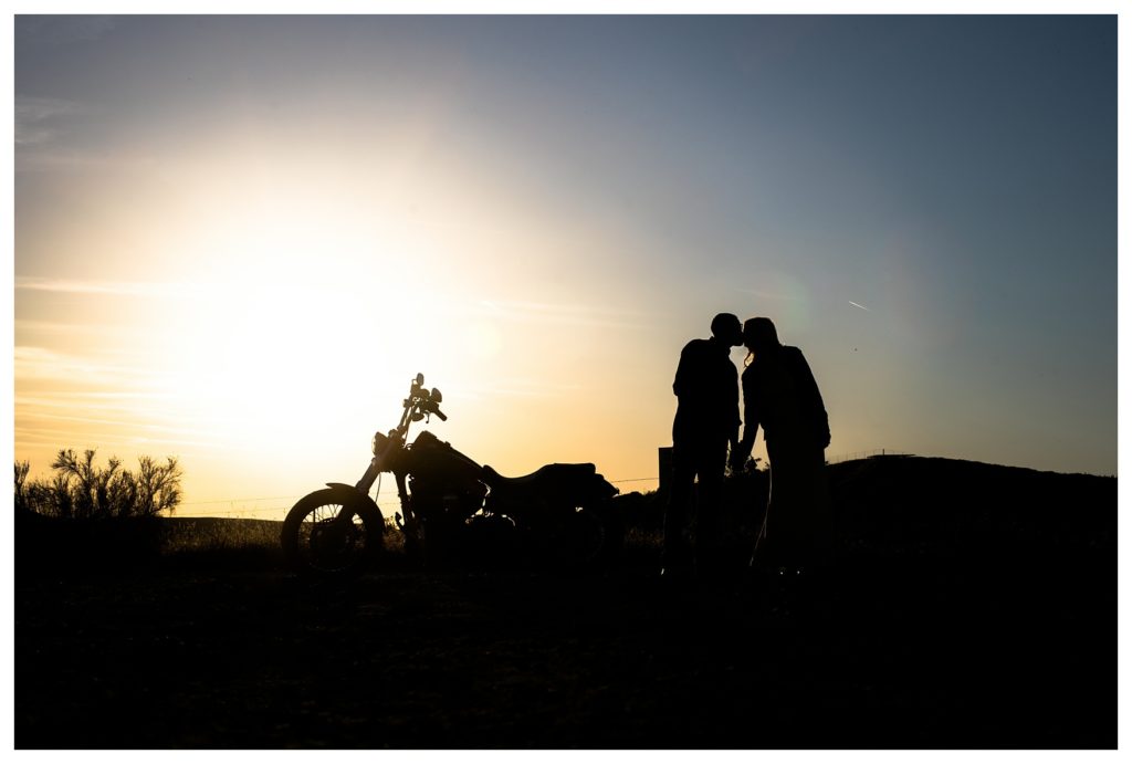 a silhouette of a couple and motorcycle during their Harley Davidson engagement photos