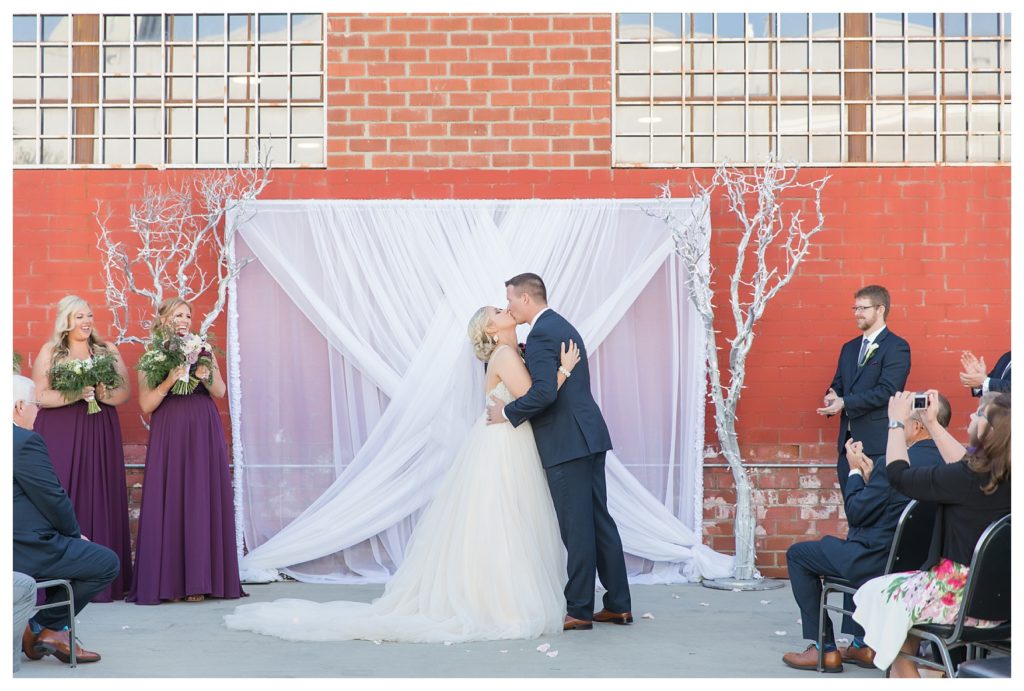 a bride and groom have their first kiss during a wedding at the Automobile Driving Museum in Segundo, California