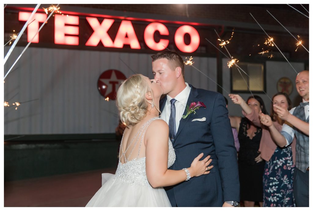 a bride and groom kiss during their sparkler exit at their wedding at the Automobile Driving Museum in Segundo, California