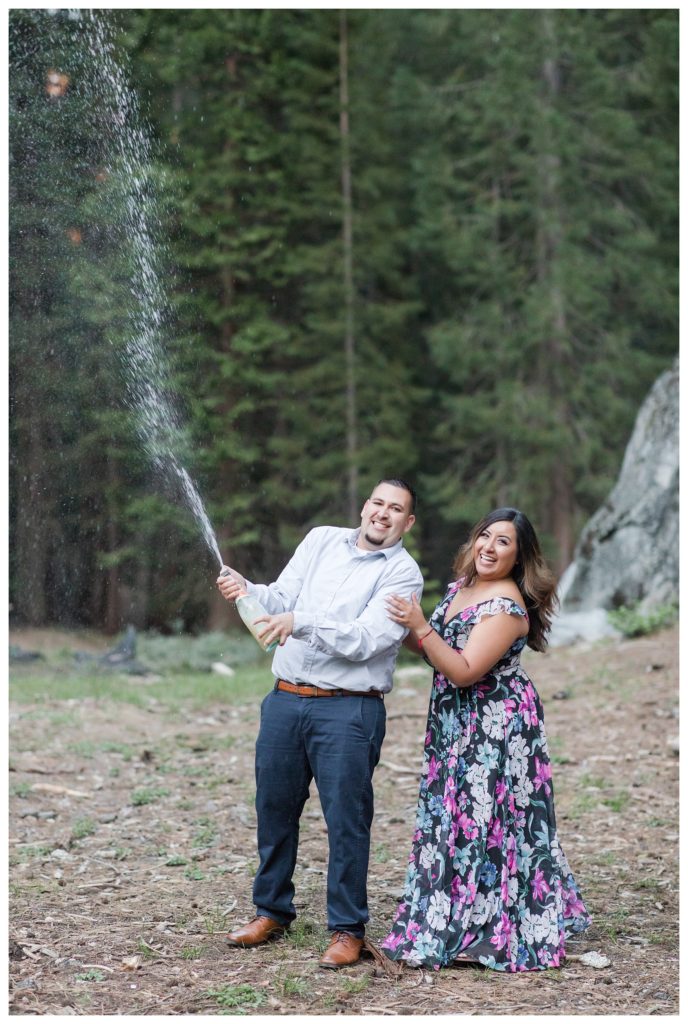 Engagement photos in Sequoia National Park - couple popping a champagne bottle in the forest