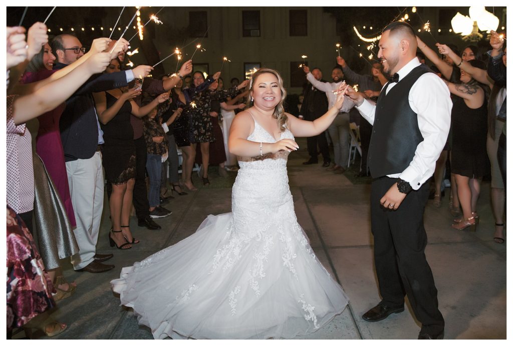 a bride and groom run through sparklers at their wedding at The Gardens at Mill Creek