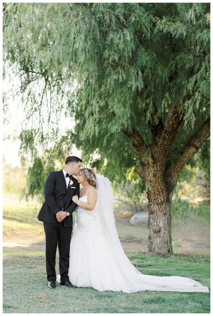 groom kisses a bride's forehead during photos at their Rio Bravo Country Club wedding