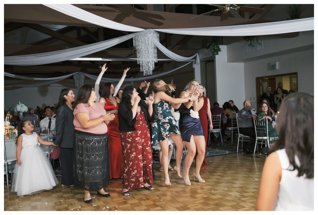 women fight over a bouquet during the bouquet toss at a Rio Bravo Country Club wedding reception