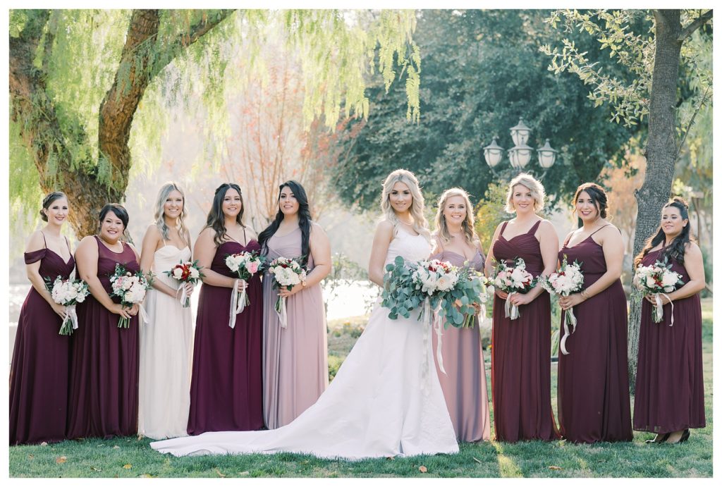 a bride and bridesmaids pose for a photo under a willow tree at a wedding at JEH Ranch