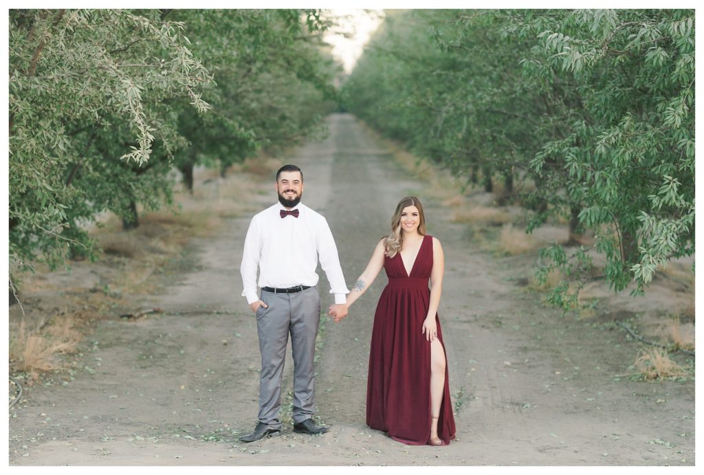 a stylish couple surrounded by a lane of trees