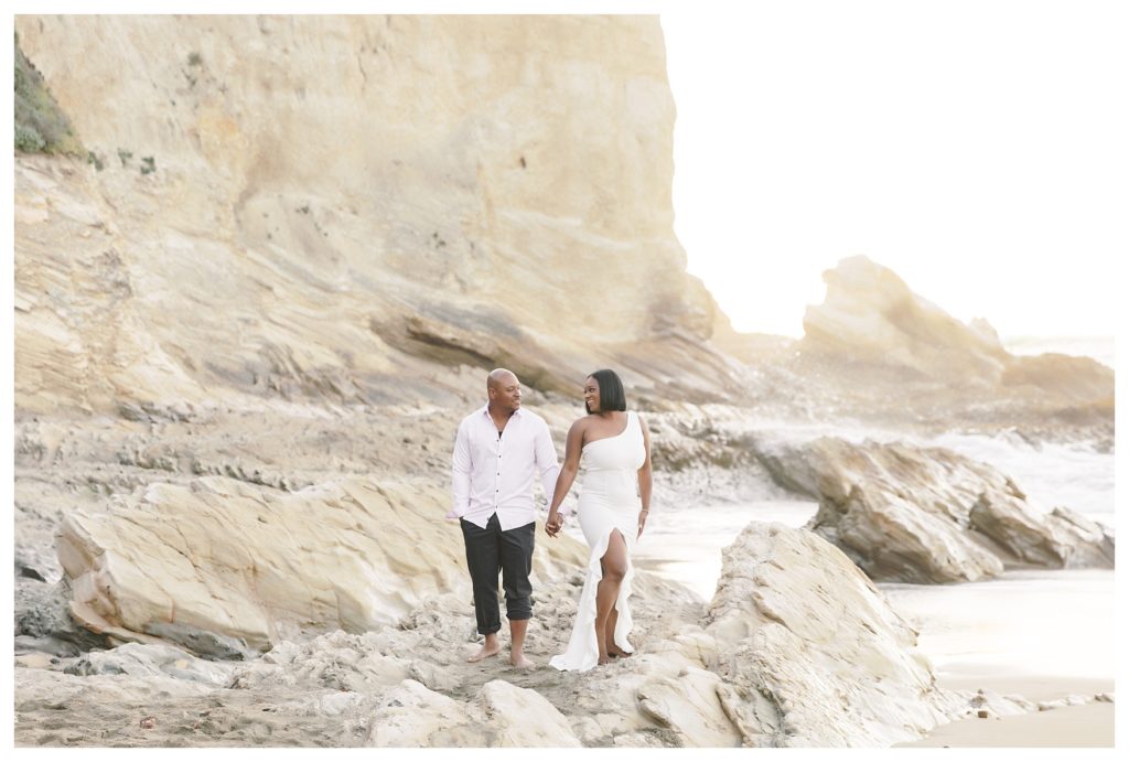 a couple walks through the beach rocks during their engagement photos at Montaña de Oro State Park