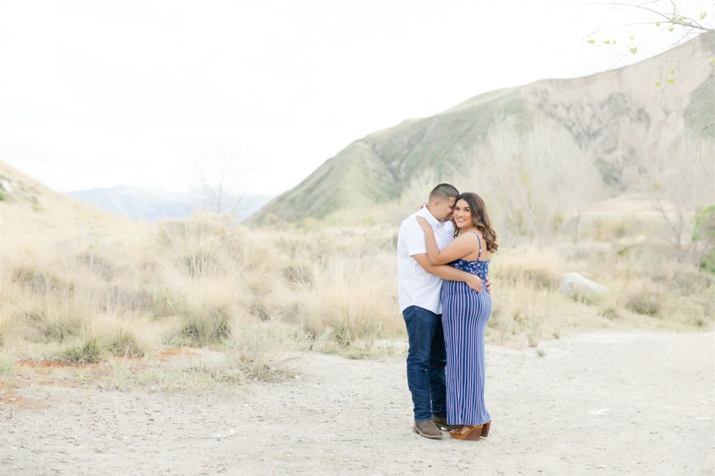 a couple poses in front of mountains during engagement photos at Wind Wolves Preserve
