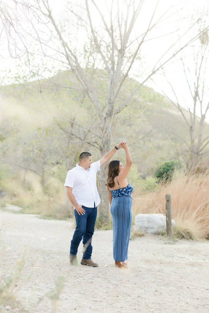 a man spins his fiancee during engagement photos at Wind Wolves Preserve
