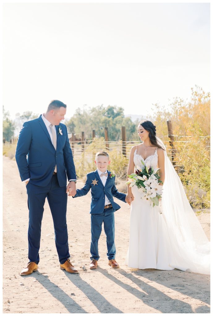 bride and groom take photos with the groom's son during their rescheduled COVID wedding