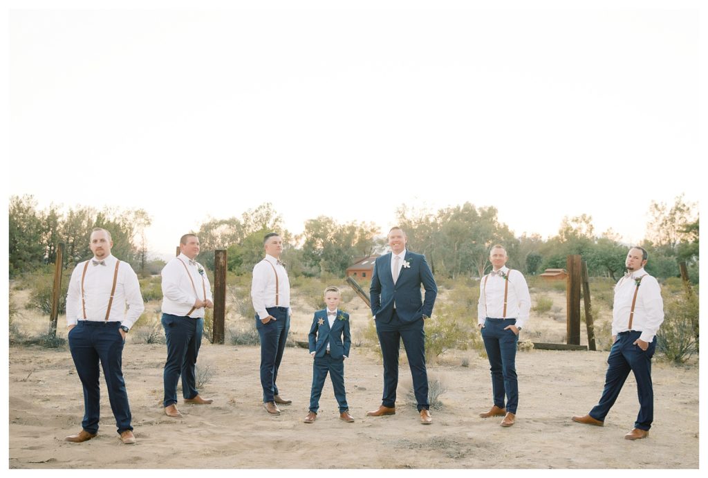 a groom poses with his groomsmen and son during his rescheduled COVID wedding photos