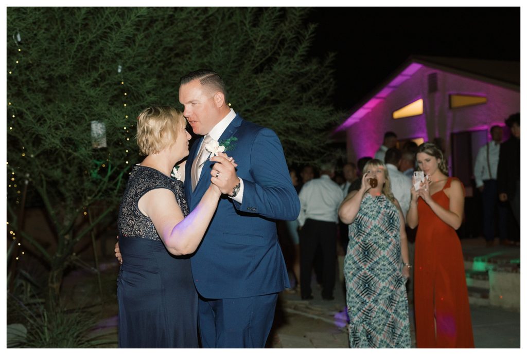 a groom dances with his mom at his rescheduled COVID wedding reception