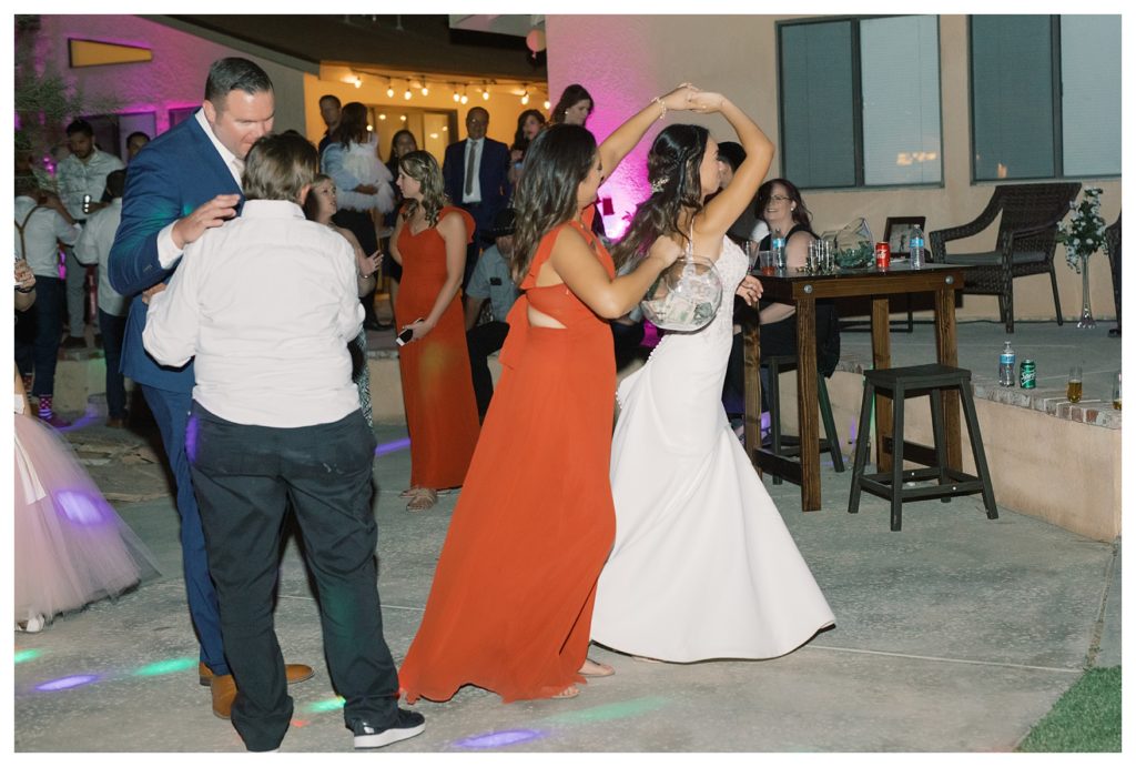 a bride dances with her bridesmaids at her rescheduled COVID wedding reception
