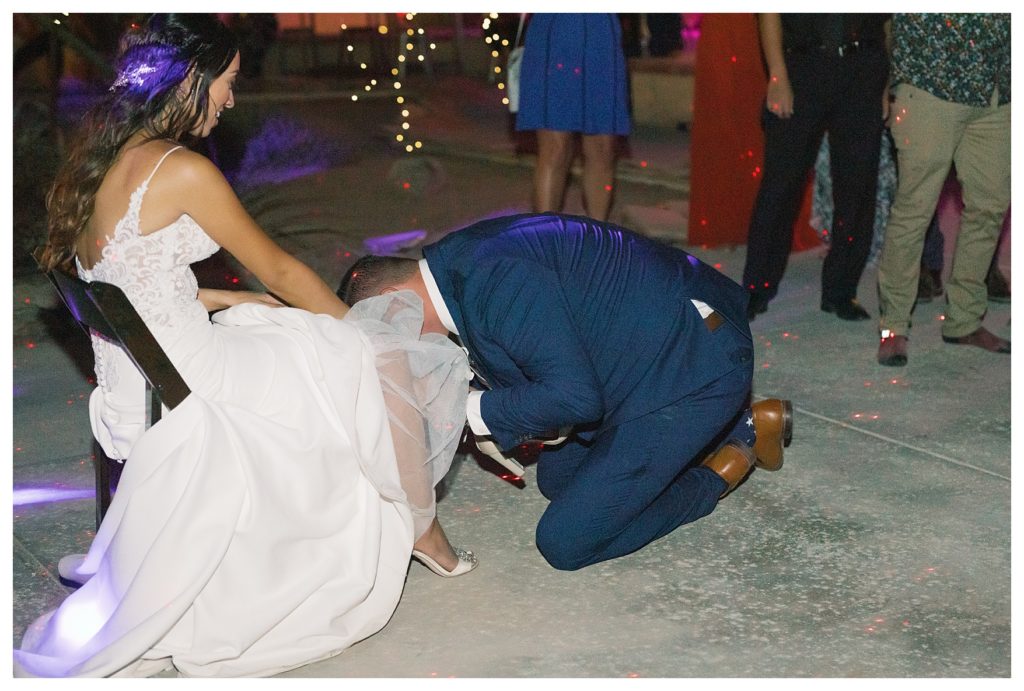a groom searches for the bride's garter at a rescheduled COVID wedding reception