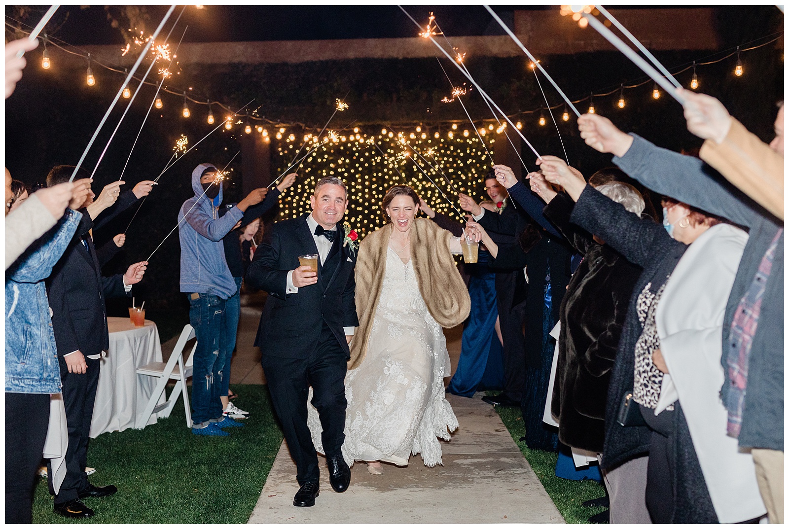 a couple runs through a line of sparklers after their winter wedding in Bakersfield, CA